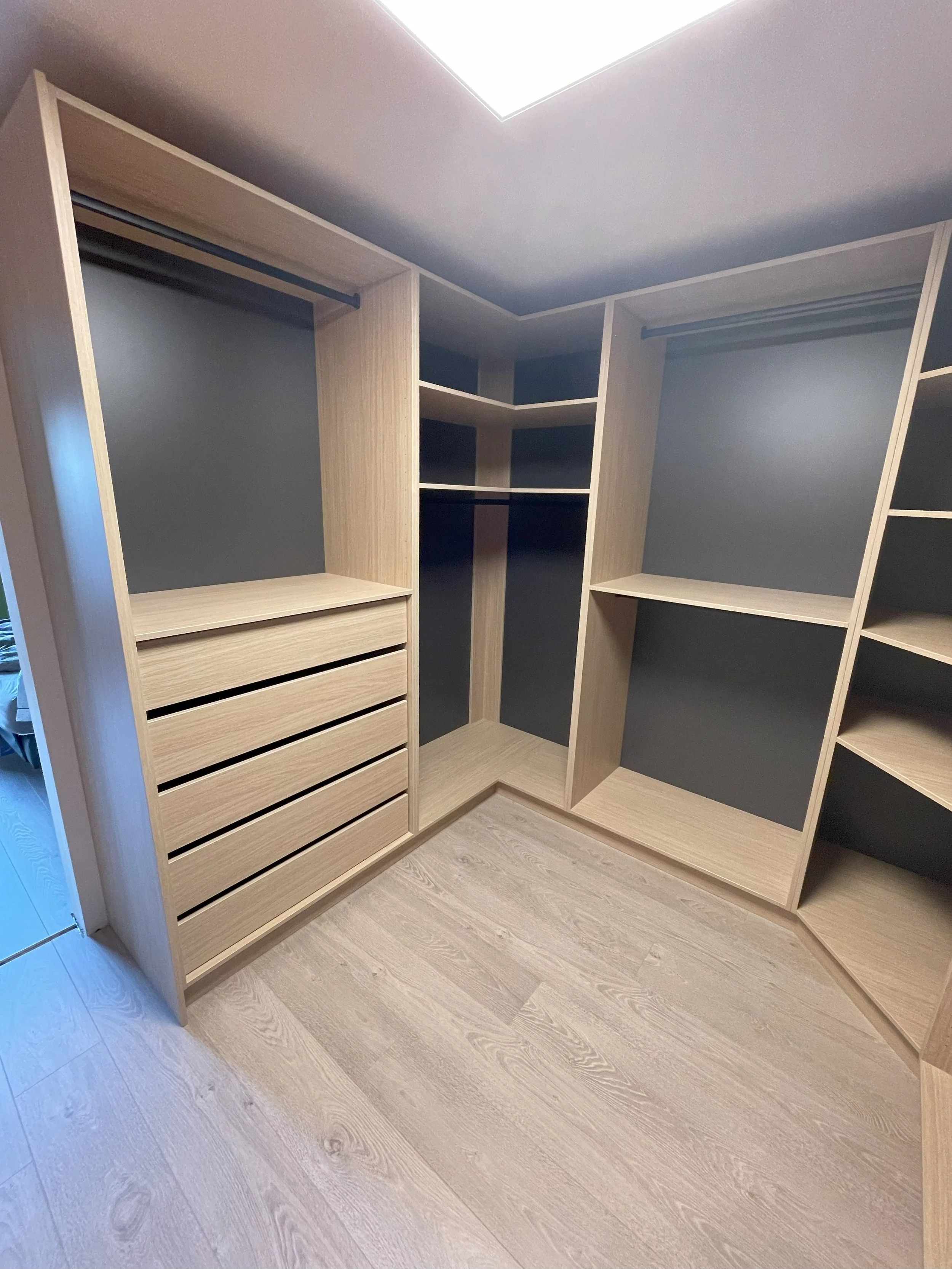Inloopdressing in licht eikendecor met open vakken, lades en achterwand in antraciet