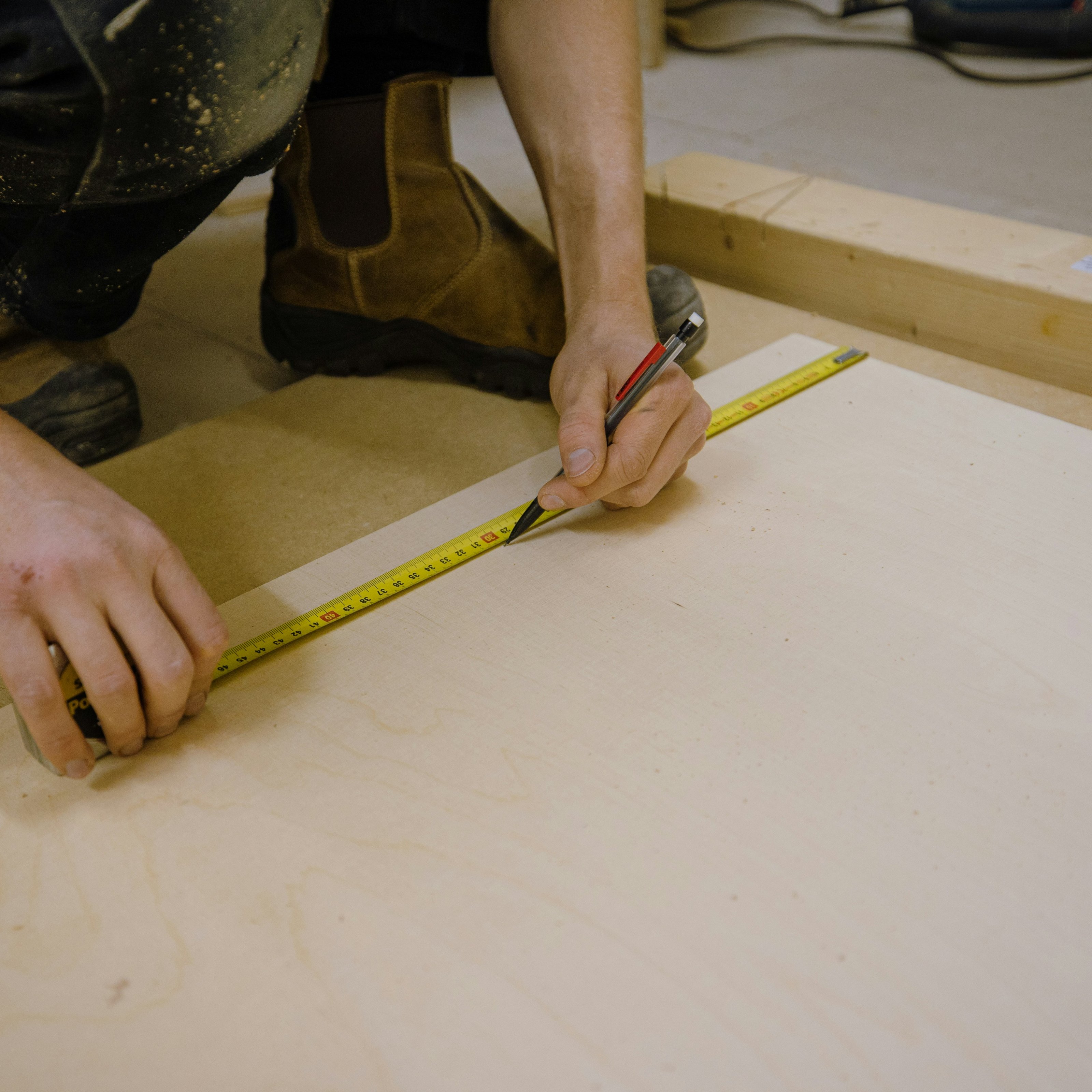Opmeten met meetlint en potlood op een houten paneel